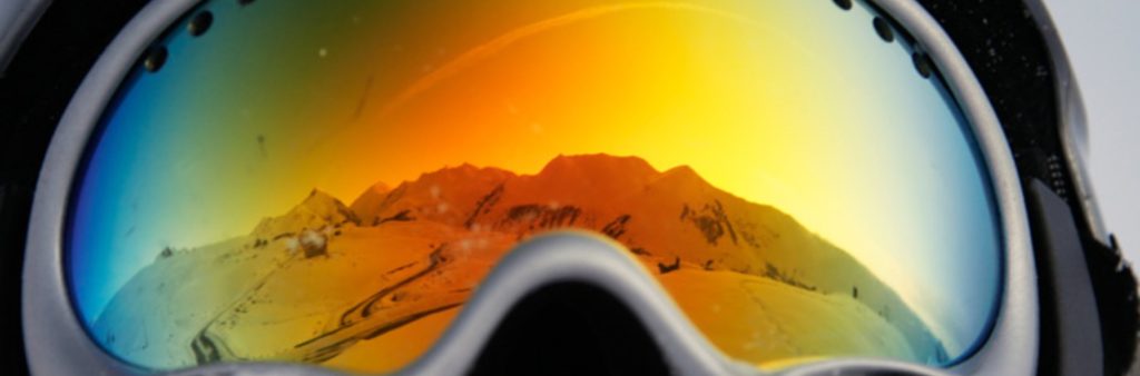 ski goggles with reflection of snow on mountains